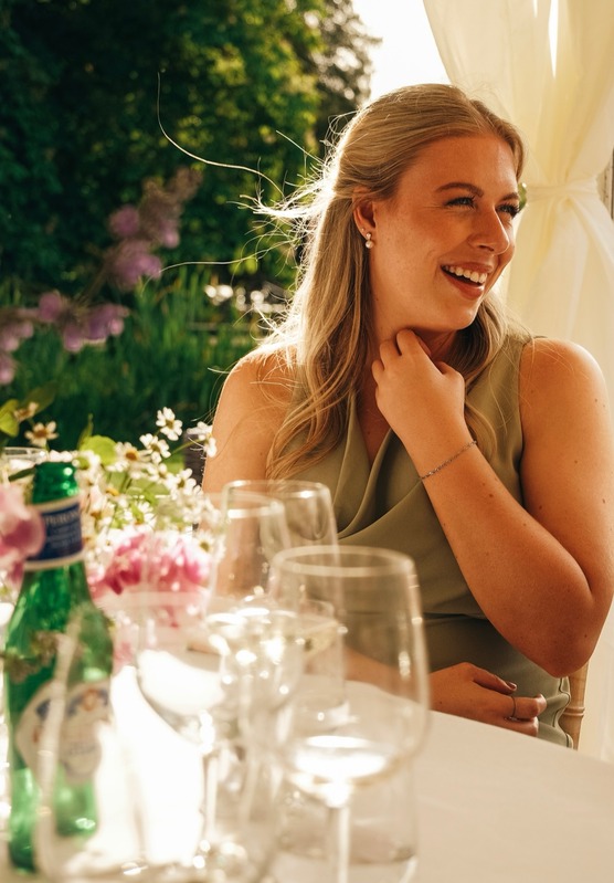 A guest laughing in golden light at a garden reception